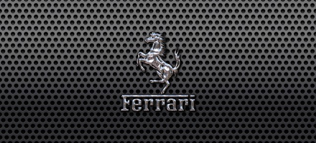 Ferrari Prancing Horse of Maranello logo on a black metal mesh wallpaper 1440x900